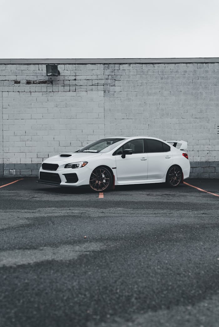 White sports car parked against a rustic brick wall, showcasing modern design.